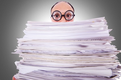 person peering over stack of paper
